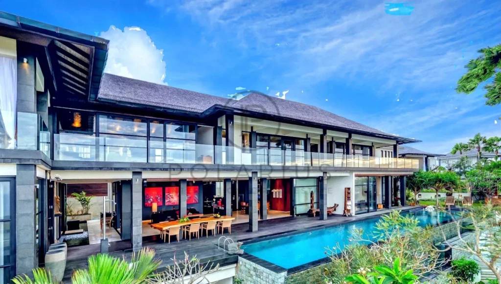 Grande villa moderne avec piscine et jardin, sous un ciel bleu.