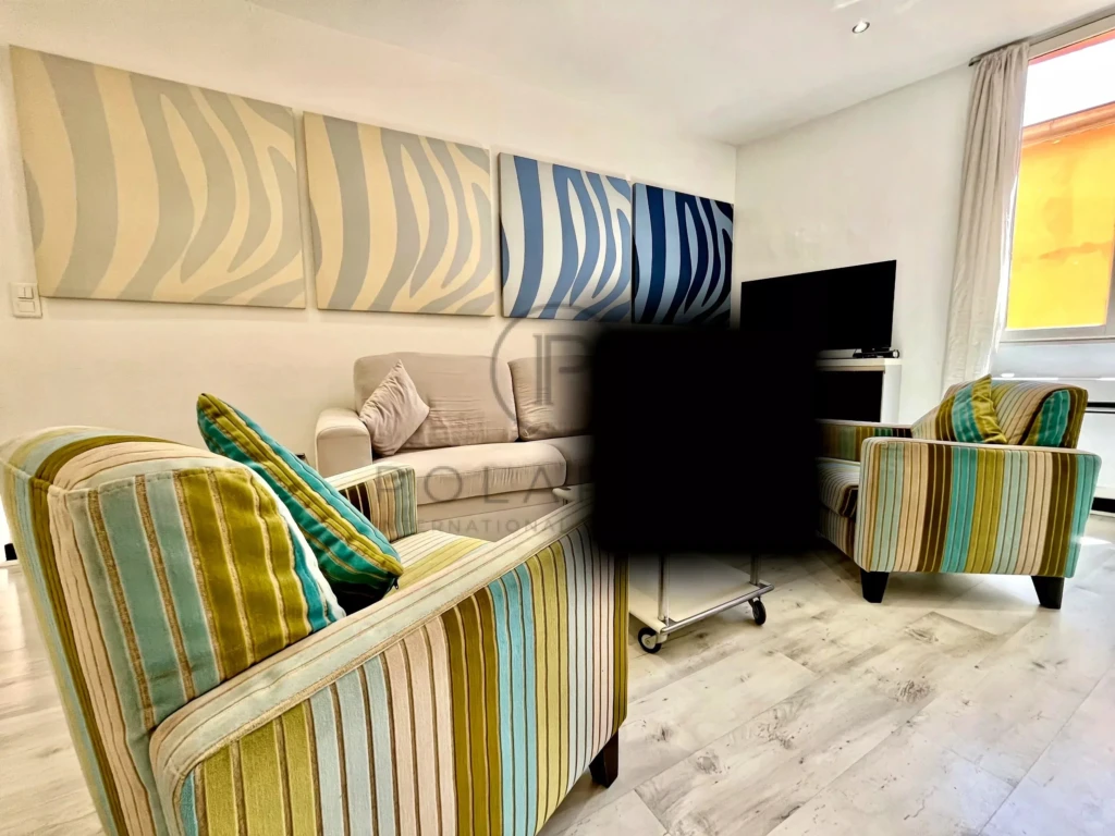 Salon lumineux avec mobilier coloré et vue sur la fenêtre.
