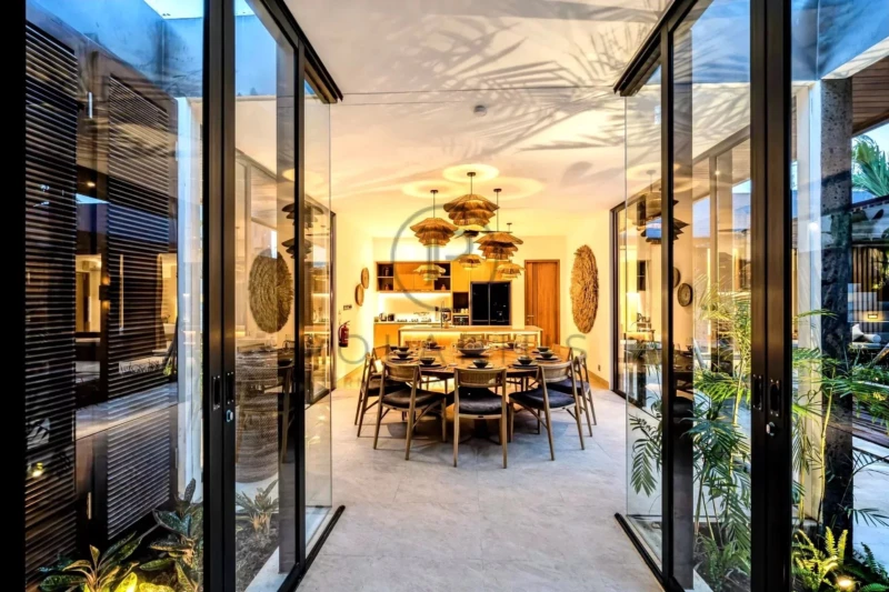 Salle à manger moderne avec une table ronde, entourée de chaises élégantes, sous un éclairage chaleureux.