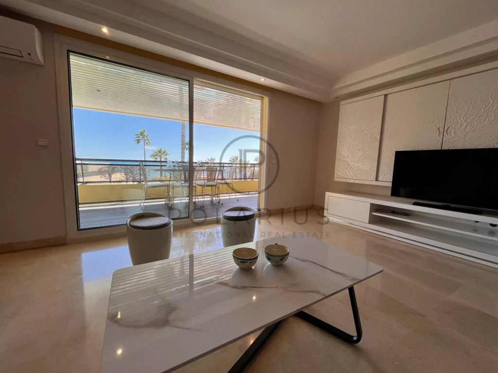 Salon lumineux avec vue sur la mer et accès à une terrasse spacieuse.