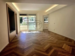 Une pièce lumineuse avec un parquet en chevron et une grande baie vitrée.