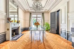 Salle à manger lumineuse avec cheminée et parquet en bois élégants.