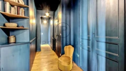 Un couloir élégant avec des murs bleus et une bibliothèque intégrée.