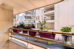 Balcon avec vue sur un immeuble résidentiel moderne, décoré de plantes et de fauteuils confortables.