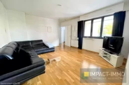 Salon spacieux avec un lustre moderne et beaucoup de lumière naturelle.