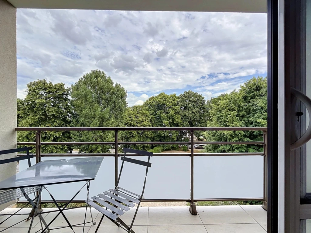 Balcon avec vue sur la verdure dans un appartement moderne.