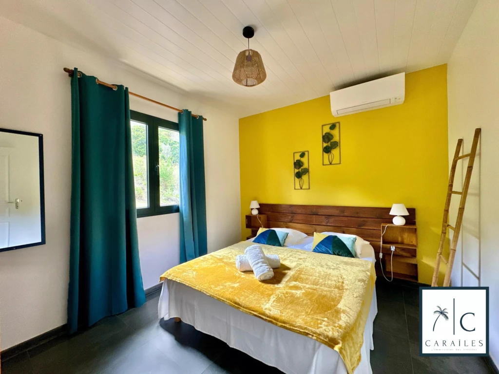 Chambre lumineuse avec un mur jaune, une grande fenêtre et une décoration moderne.
