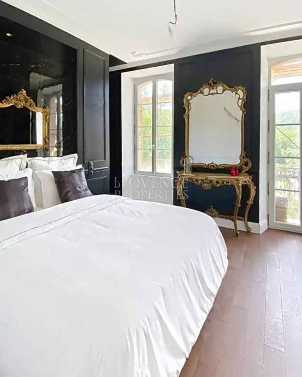 Une chambre somptueuse mariant un mur d'accent noir profond, du mobilier de style baroque doré et de magnifiques volumes ouverts sur l'extérieur.