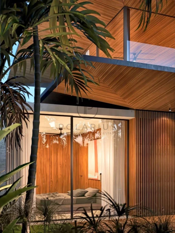 Une maison moderne avec des murs en bois, de grandes fenêtres et entourée de végétation tropicale.