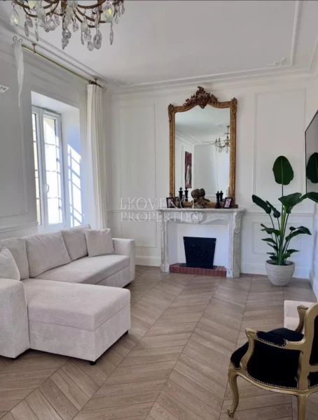 Vaste espace de vie associant le charme de l'ancien et le confort moderne : parquet en chevrons, moulures raffinées et cheminée d'époque.