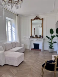 Vaste espace de vie associant le charme de l'ancien et le confort moderne : parquet en chevrons, moulures raffinées et cheminée d'époque.