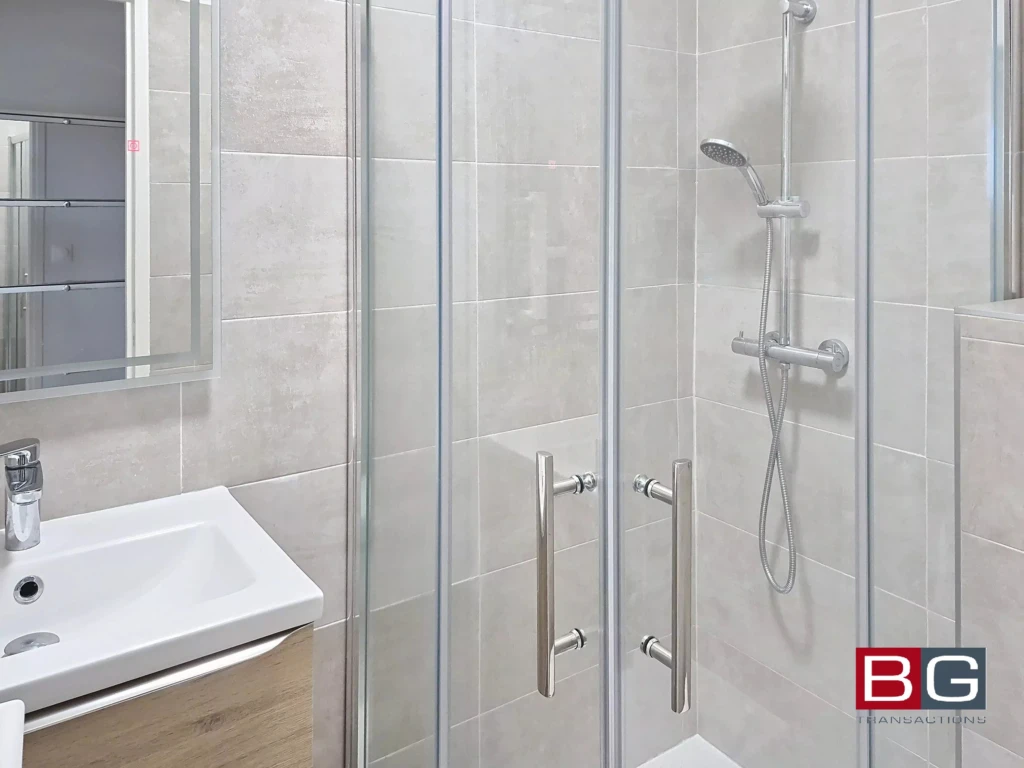 Salle de bain moderne avec douche en verre et lavabo élégant.
