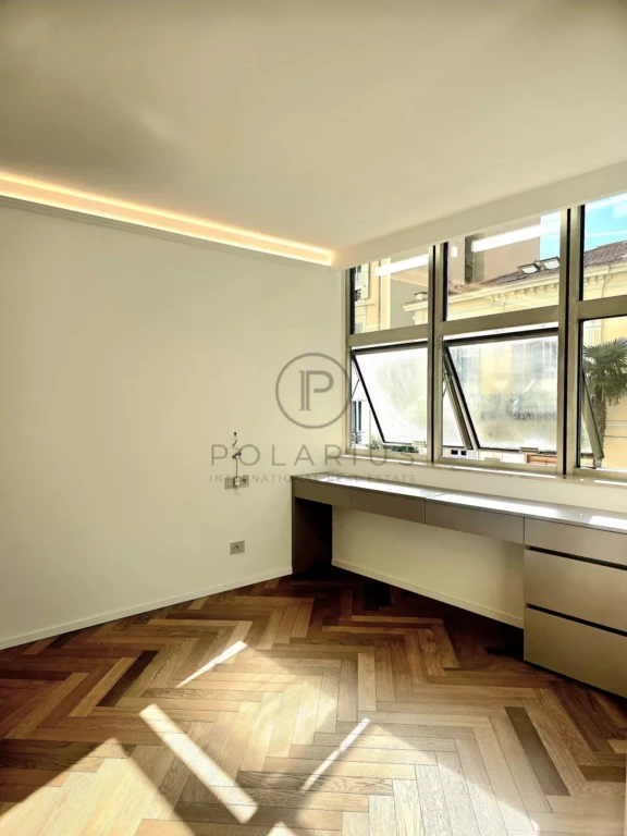 Une pièce lumineuse avec un parquet en bois et un bureau intégré sous de grandes fenêtres.