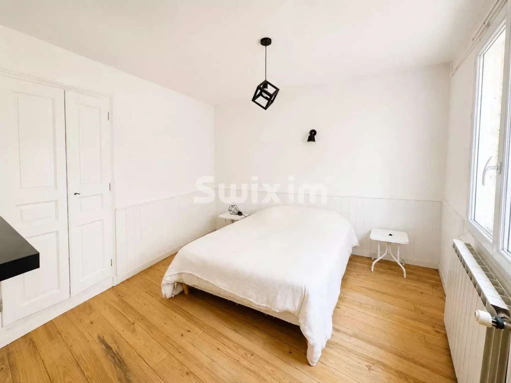 Chambre lumineuse avec un lit confortable et un parquet en bois chaud.