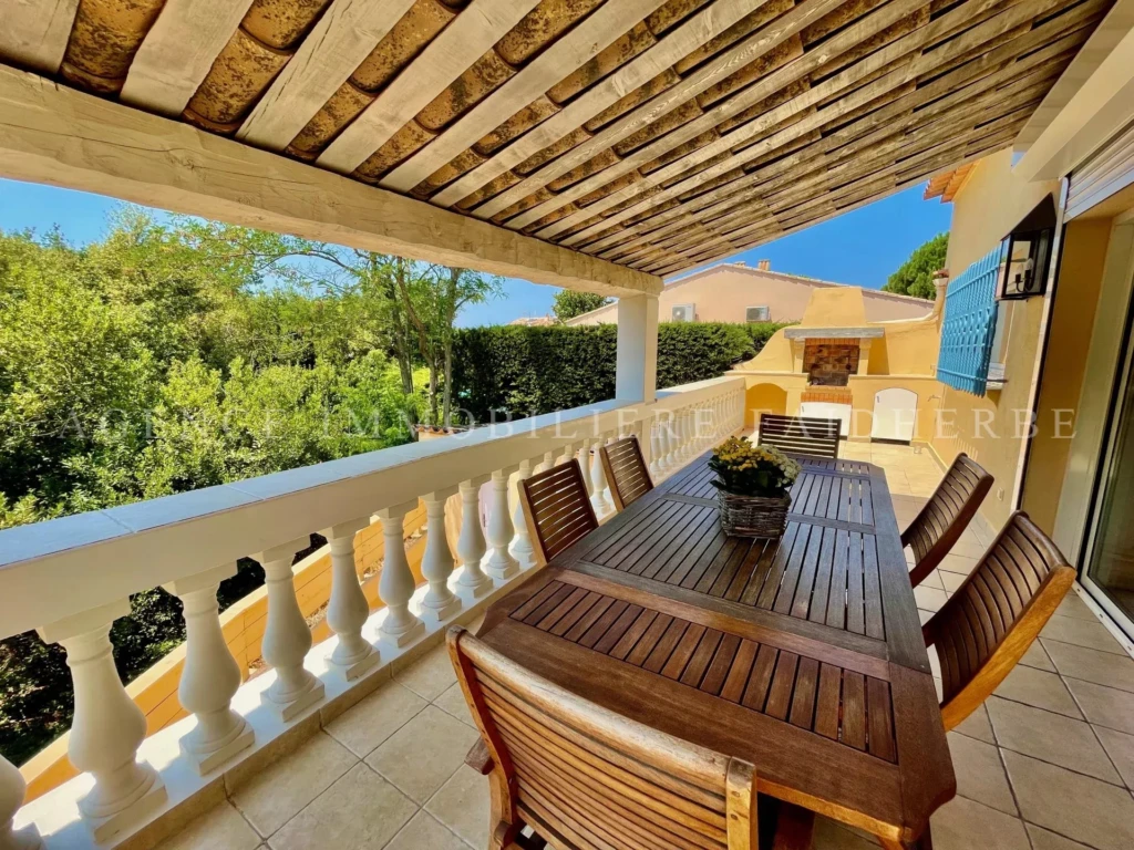 Balcon avec table en bois et vue sur la verdure dans une propriété conviviale.