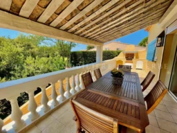 Balcon avec table en bois et vue sur la verdure dans une propriété conviviale.