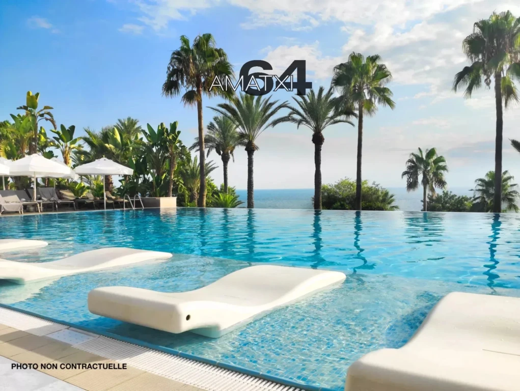 Stunning resort pool, surrounded by loungers, palms, and ocean views, is perfect for a getaway