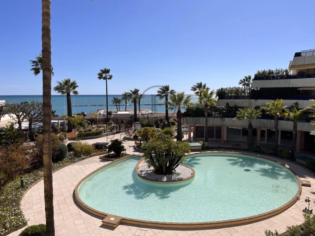 Piscine extérieure avec vue sur la mer et palmier, idéal pour la détente.