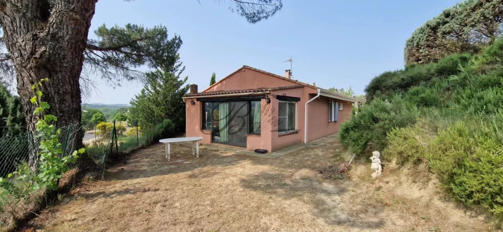 LA TOUR D'AIGUES, A small pink house with a tiled roof is situated in a grassy area surrounded by tr