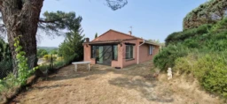 LA TOUR D'AIGUES, A small pink house with a tiled roof is situated in a grassy area surrounded by tr