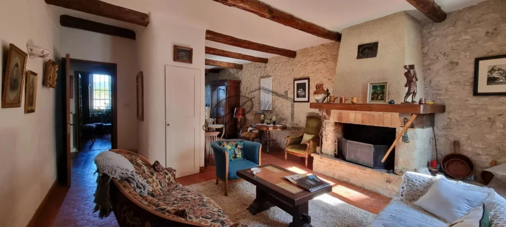 LA BASTIDE DES JOURDANS, A cozy, rustic living room with stone walls, wooden beams, and vintage furn