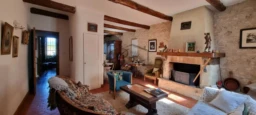 LA BASTIDE DES JOURDANS, A cozy, rustic living room with stone walls, wooden beams, and vintage furn