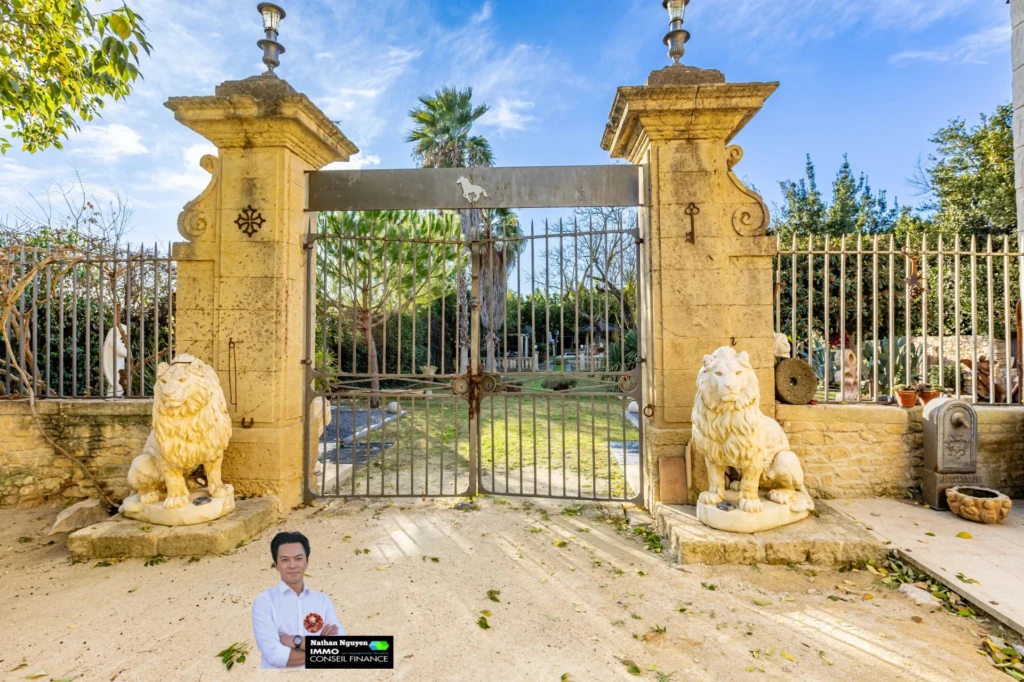 Belle propriété avec un grand portail en fer forgé donnant à un jardin